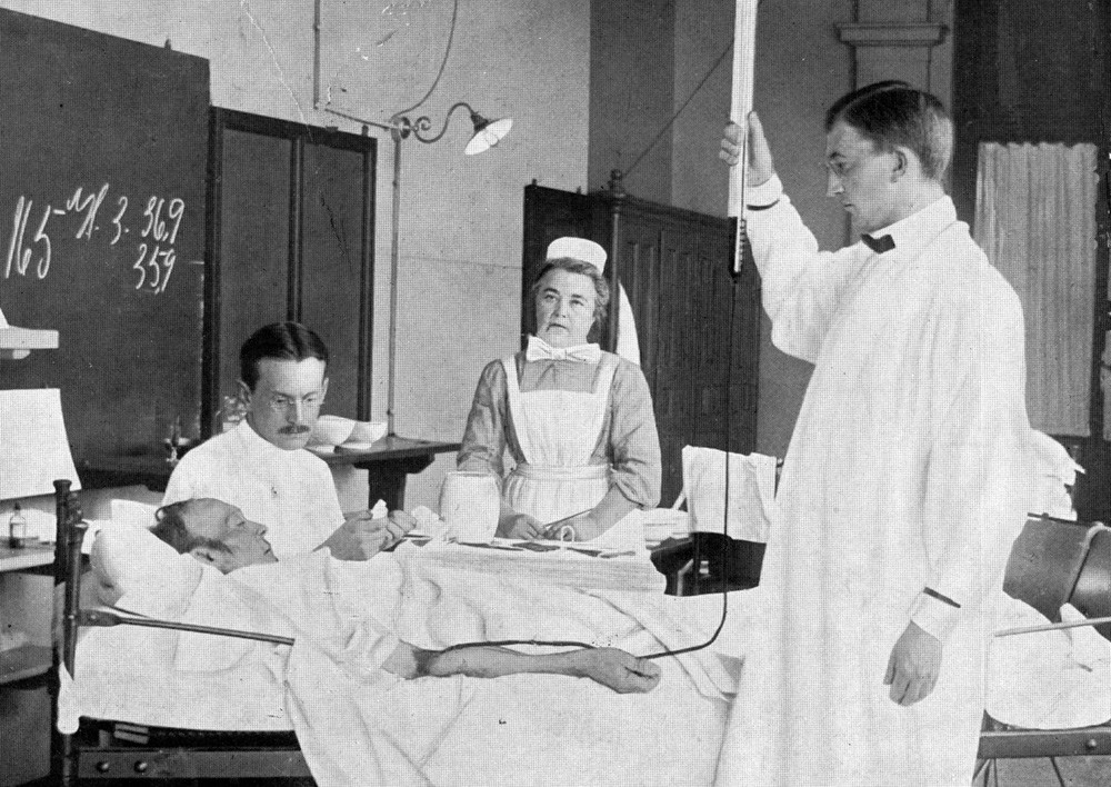 Figur 2  Transfusjon ved Rikshospitalet ca. 1912. Blodet er defibrinert og blir gitt fra m&aring;lesylinder i &aring;pent system. Bemerk&hellip;